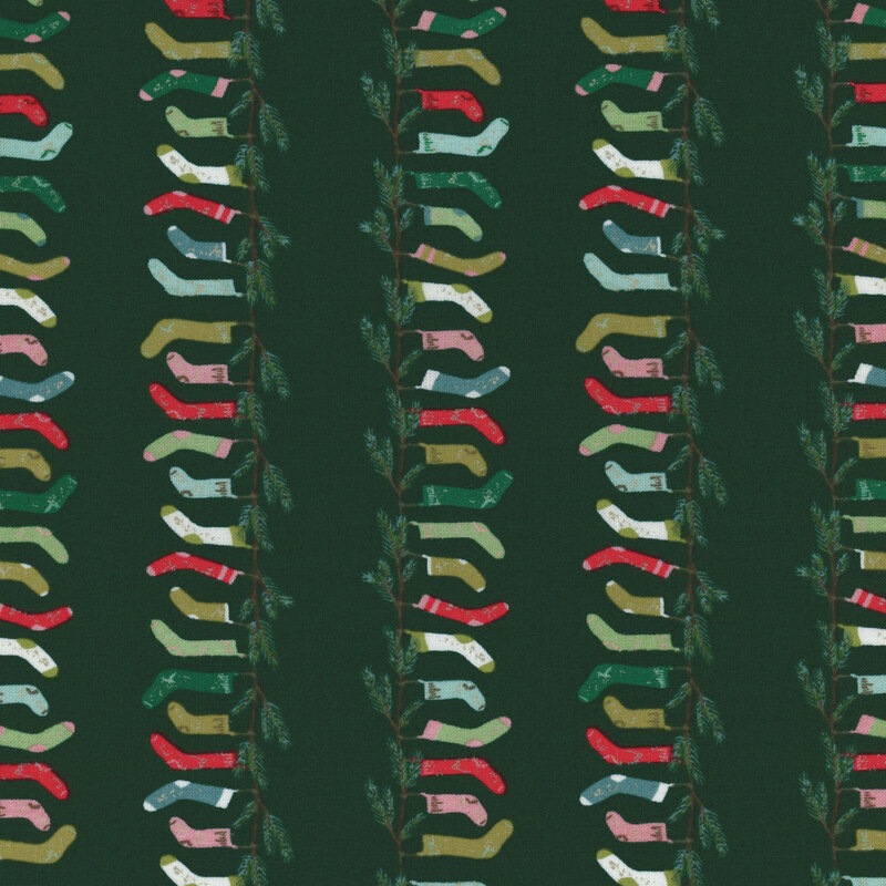 pine green fabric with rows of fir branches with hanging stockings in shades of pink, red, green, and aqua