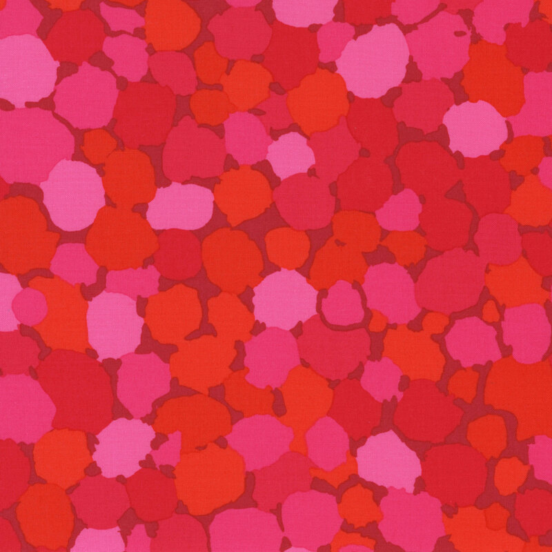 Fabric featuring vibrant pink, orange, and red abstract dots over a maroon background
