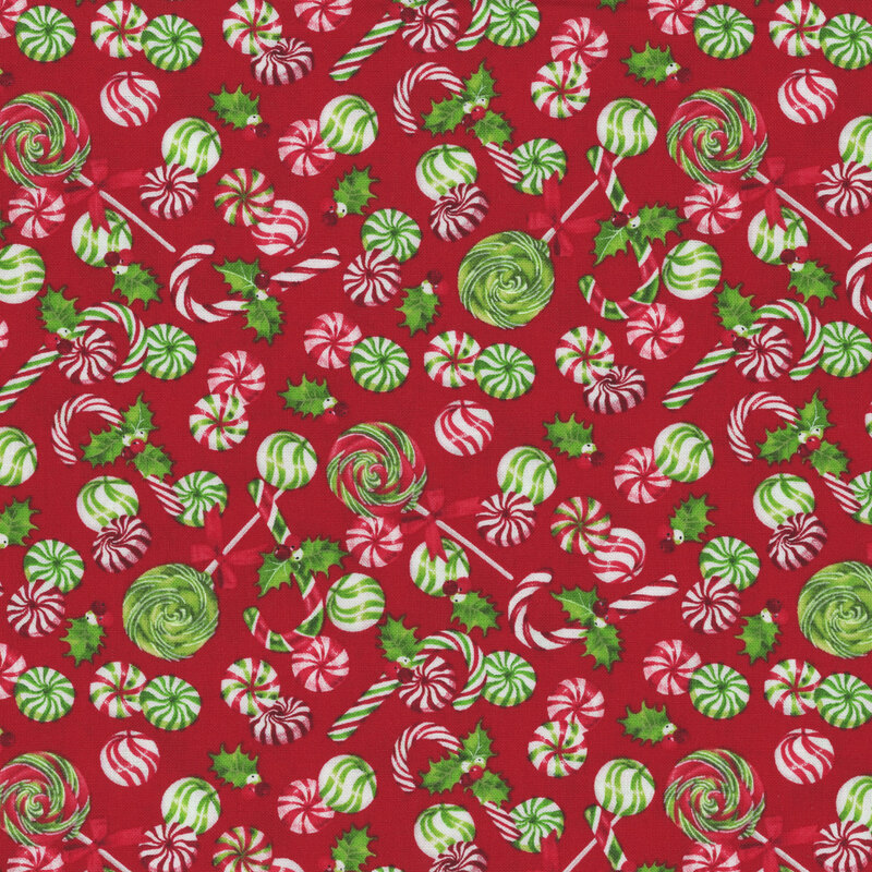 Tossed holiday candies on a berry red fabric.