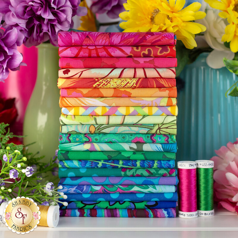stack of botanical fabrics in rainbow colors surrounded by flowers