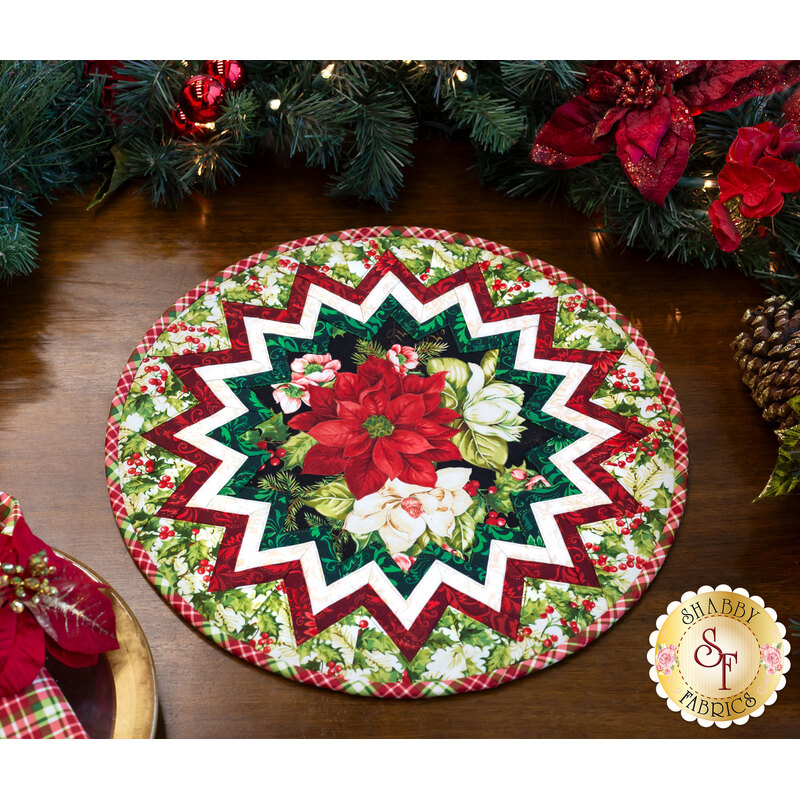 Photo of a Christmas table topper on a wooden table with garland and poinsettias all around