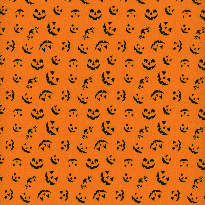 Pumpkin orange fabric with tossed jack o lantern faces all over.