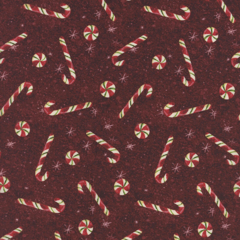 snowflake covered wine red fabric adorned with scattered red candy canes and peppermint swirl candies