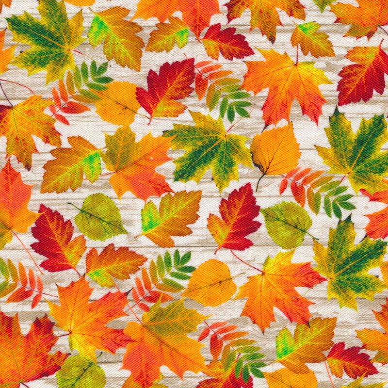 fabric with leaves in shades of red, orange, and green on a white wood-textured background