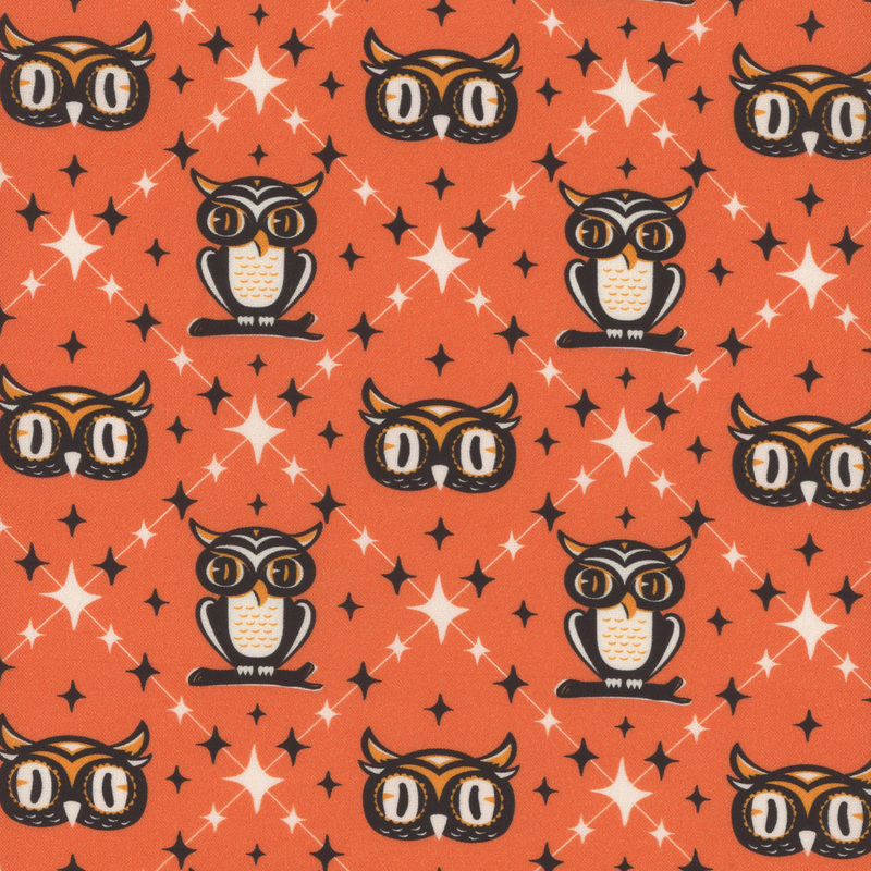 orange fabric with a square on point design surrounding stylized black, orange, and white owls and owl heads amidst scattered 4-pointed stars.
