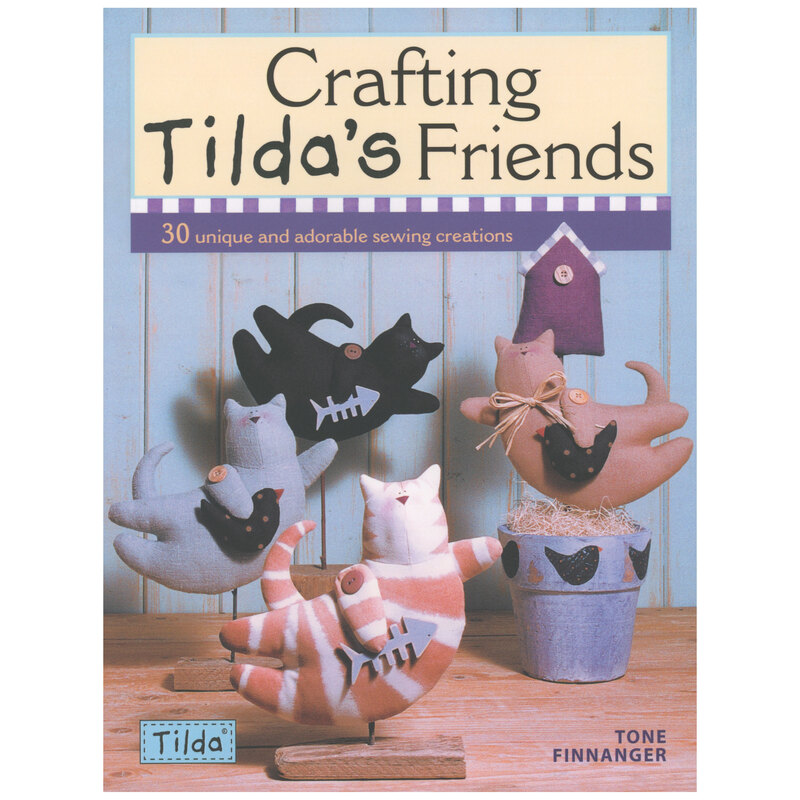 Front cover of book showing four adorable soft cat dolls in various colors, staged on a wooden table.