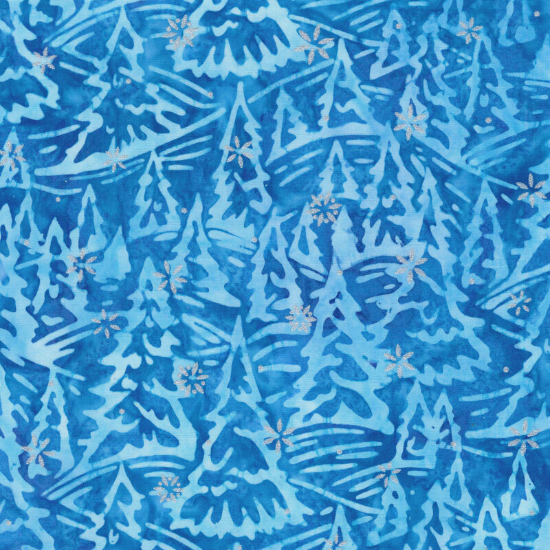 blue mottled fabric featuring rolling hills of fir trees in shades of mottled light blue and white and accented with metallic silver snowflakes