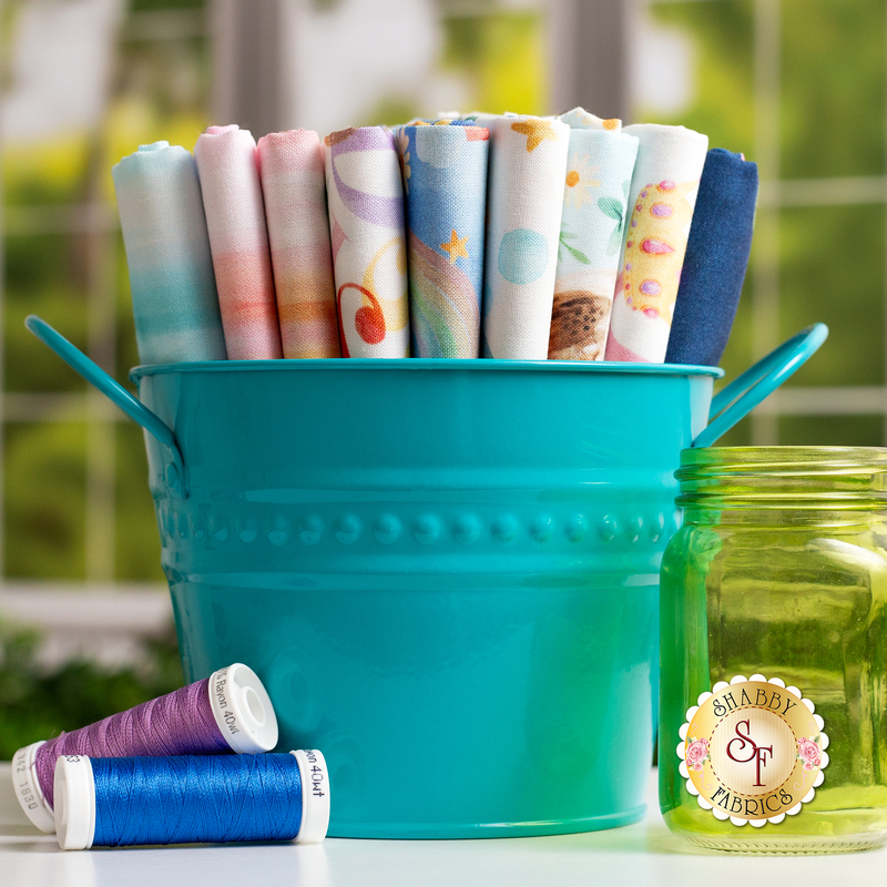 Photo of 9 fabrics in the Love and Learning collection set in a teal bucket with thread spools on the left and a jar on the right 
