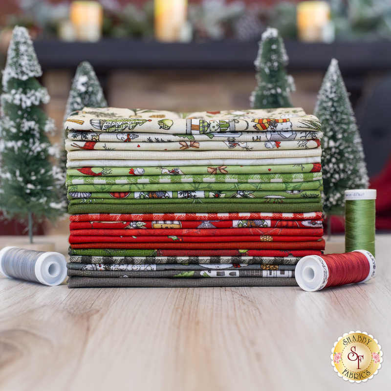 A stack of Homemade Holidays fabric surrounded by small trees and thread.