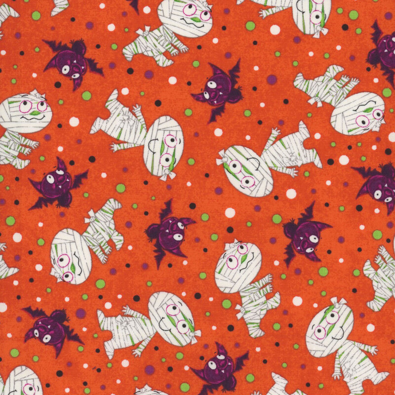 orange fabric, featuring scattered mummies and bats, with white, purple, green, and black dots sprinkled in between