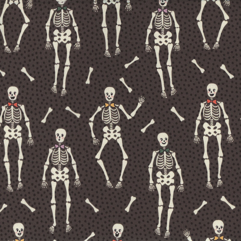 Dark gray fabric with tiny black dots close together and upright bow tie wearing skeletons with long bones tossed between them