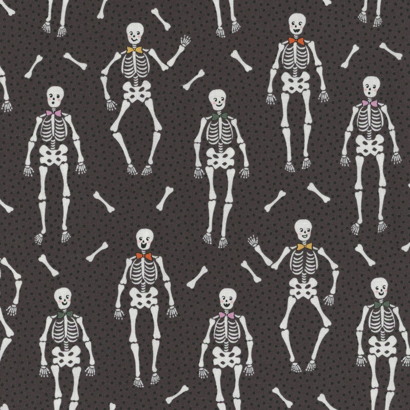 Dark gray fabric with tiny black dots close together and upright bow tie wearing skeletons with long bones tossed between them.