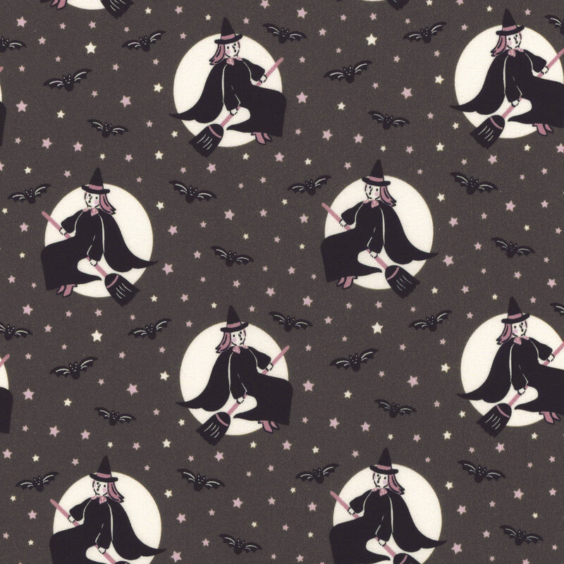 Dark gray fabric featuring white stars and black bats tossed amid images of a vintage style witch riding a broomstick in front of a white moon.