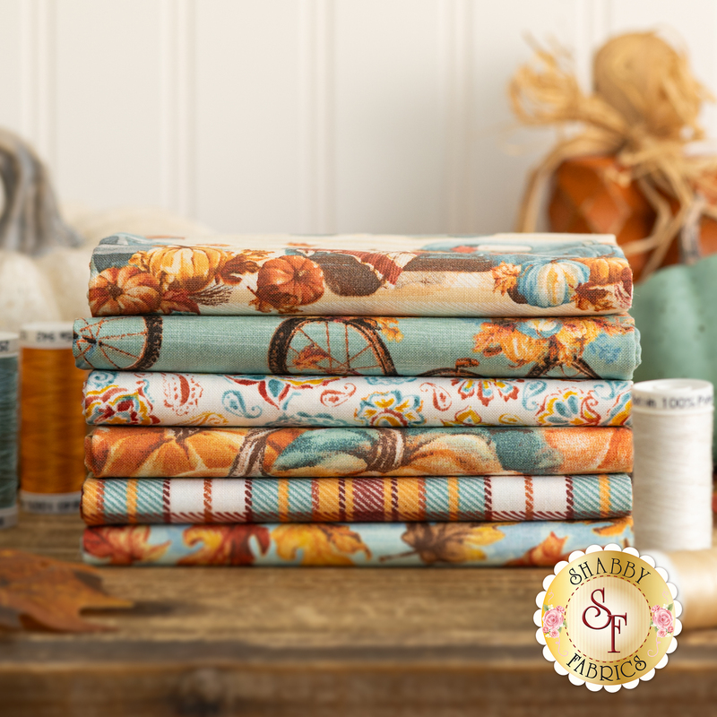 A photo of the fat quarter fabrics in teal and orange with pumpkins and fall motifs