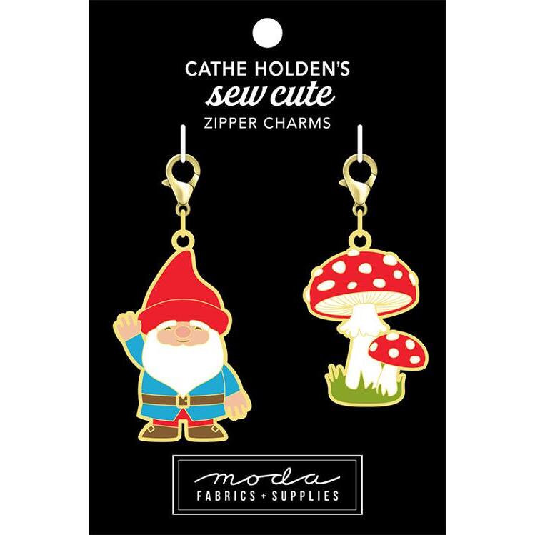 Image of a black tag with two charms, one gnome and one red mushroom themed zipper pull