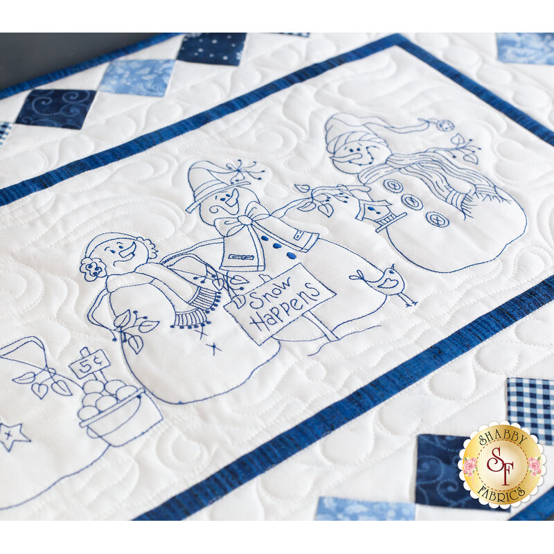 A closer look at the embroidered snowmen on the right side of the runner, detailed in blue embroidery thread.