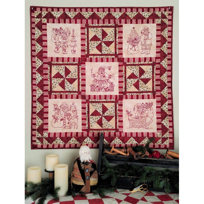The complete Believe in Santa quilt, staged above a table with candles and vintage bobbins.