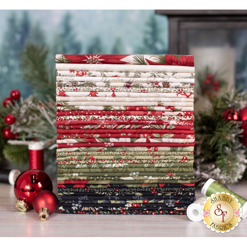a stack of christmas fabric in muted shades of red, green, cream, and black surrounded by a holiday garland
