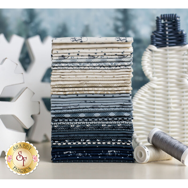 stacked fabrics in a lovely gradient from cream to a dark, dusty blue, in front of a snowy scene