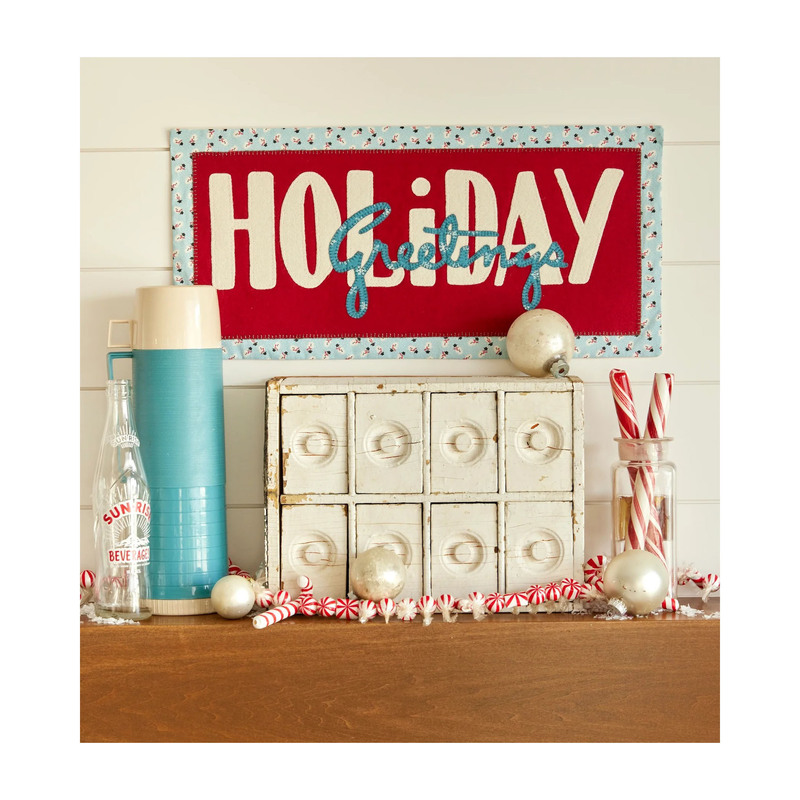 Front of the pattern showing the completed wall hanging staged above a rustic set of white drawers and various candy cane decor.