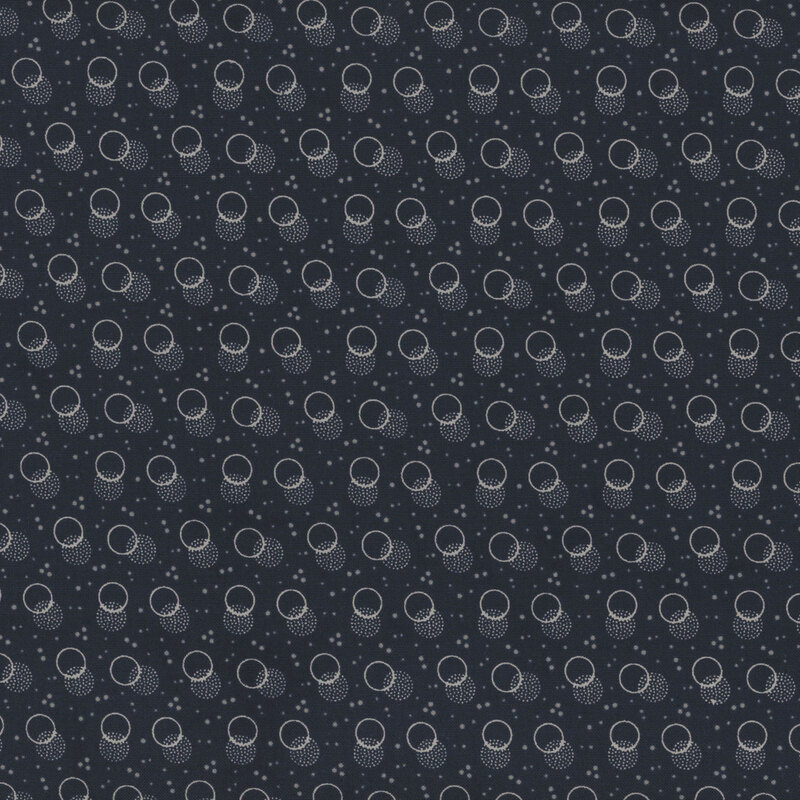 navy blue fabric with light blue speckling and layered off white circles and stippled polka dots