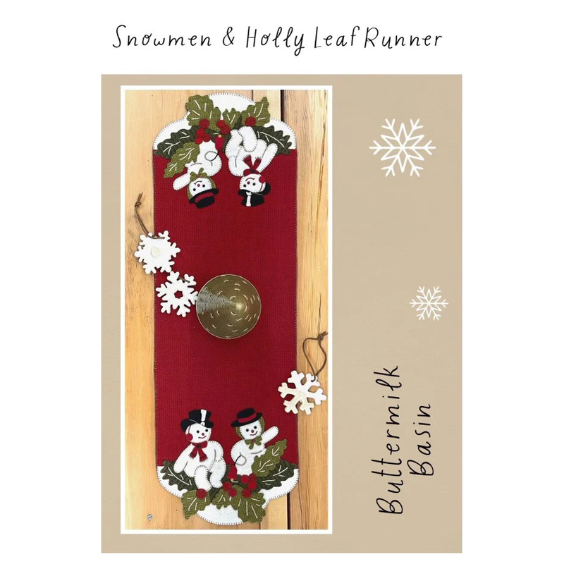 Front of the pattern showing the completed runner in deep red on a rustic wood table, staged with snowflake ornaments.
