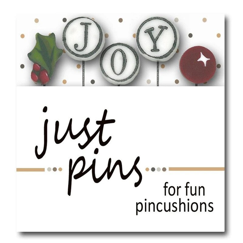 A digital mockup of the packaging for the pins, which includes holly, a red berry, and three letters, J, O, and Y. 