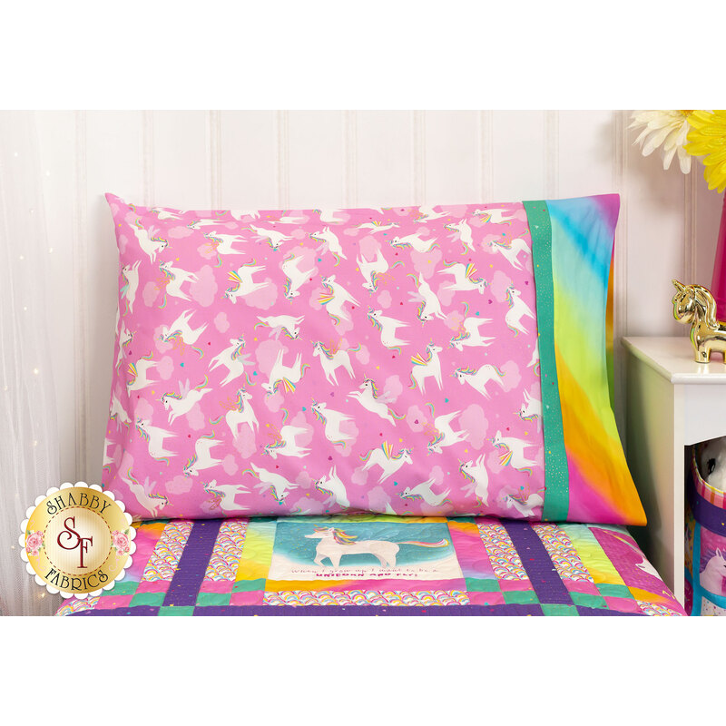 The completed pink pillowcase, staged on a bed with the Unicorn Love quilt beside a white nightstand with coordinating decorations.