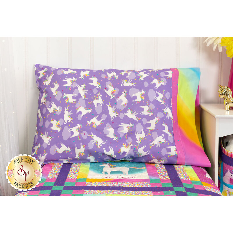 The completed purple pillowcase, staged on a bed with the Unicorn Love quilt beside a white nightstand with coordinating decorations.