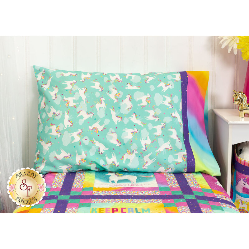 The completed teal pillowcase, staged on a bed with the Unicorn Love quilt beside a white nightstand with coordinating decorations.