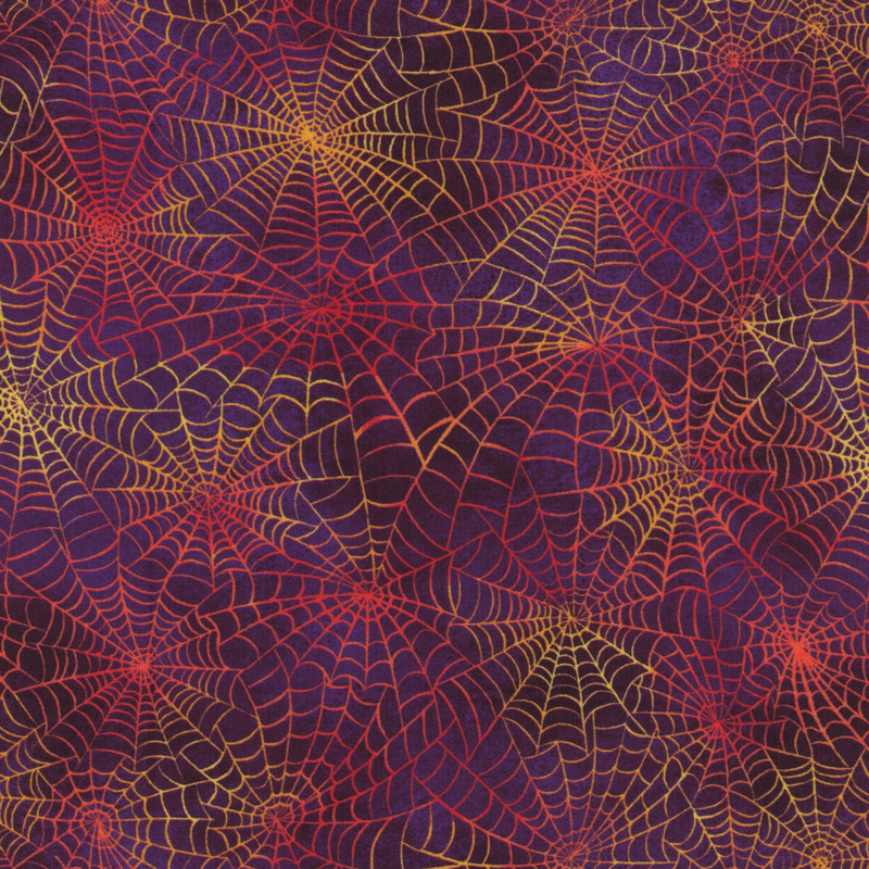Mottled purple fabric with orange  and yellow spider webs all over.