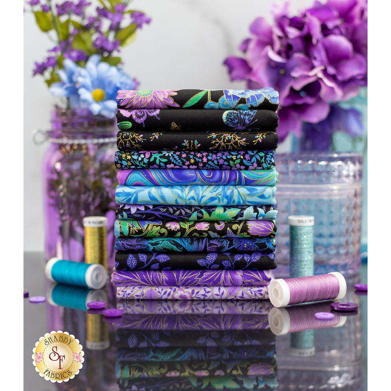 A stack of Luminous fabric surrounded by florals and threads.