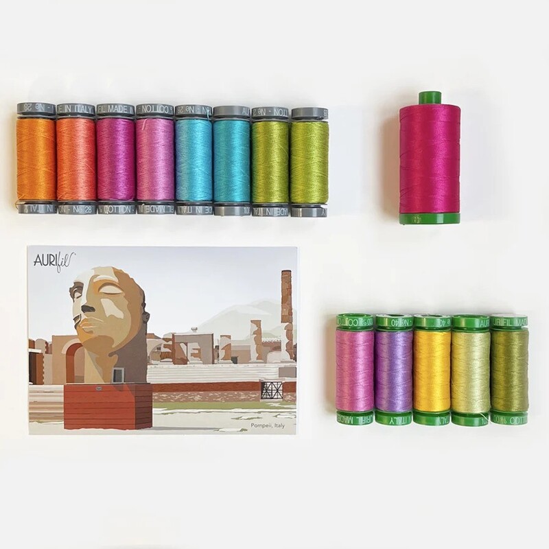 The contents of the third box, 14 spools of thread and a postcard, spread out and isolated on a white background.