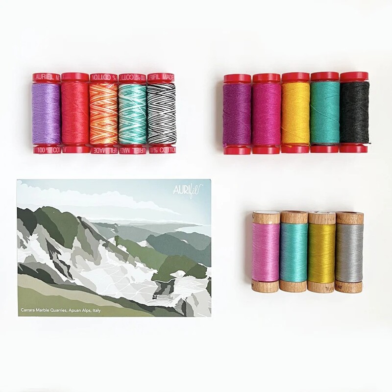 The contents of the fourth box, 14 spools of thread and a postcard, spread out and isolated on a white background.