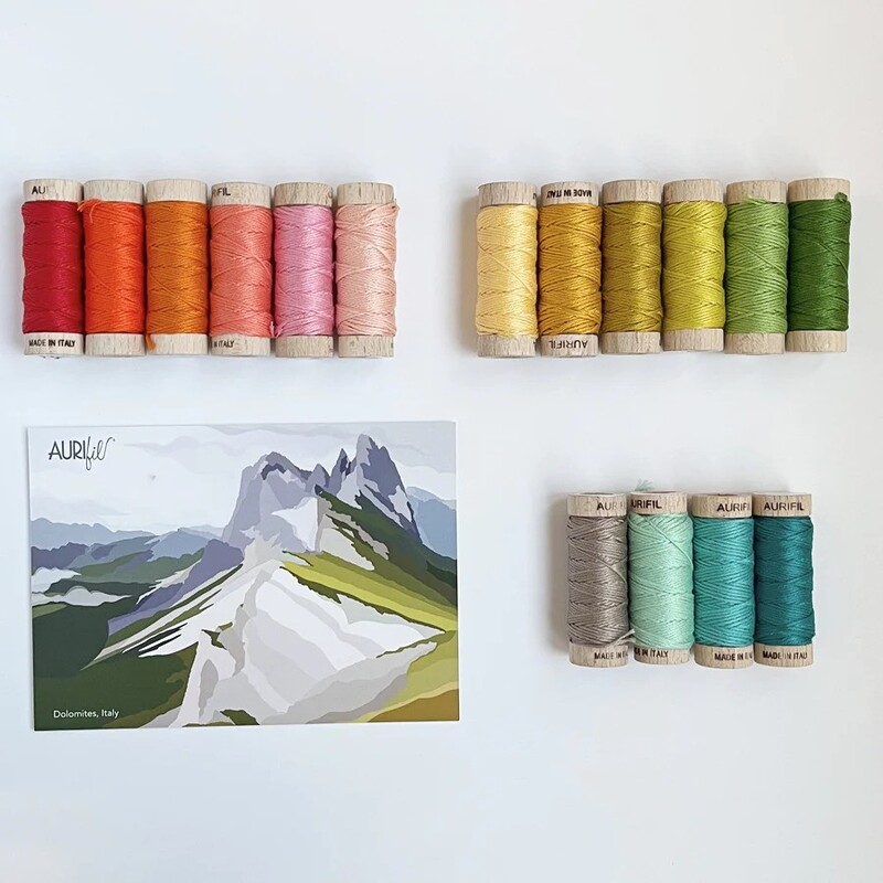 The contents of the fifth box, 14 spools of thread and a postcard, spread out and isolated on a white background.