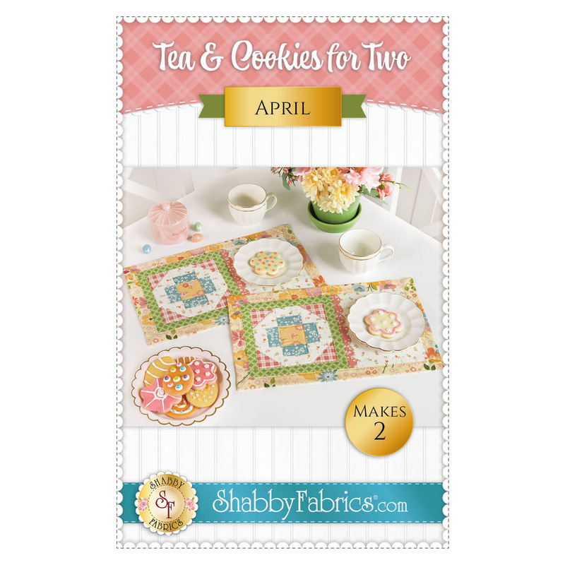 Front cover of the pattern showing the two completed April placemats staged on a white table with white tea cups, plates of coordinating decorated cookies, and a green pot of spring flowers.