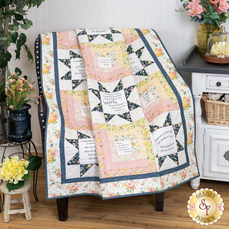 A shot of the quilt, artfully draped over a chair and staged with coordinating housewares like a side table, ficus, flowers, and other small decor.