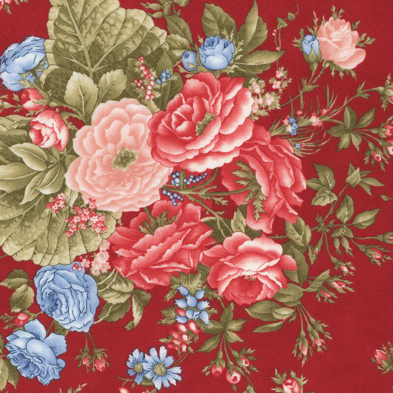 A section of fabric a red fabric with large pink, red and blue florals with large green leaves.