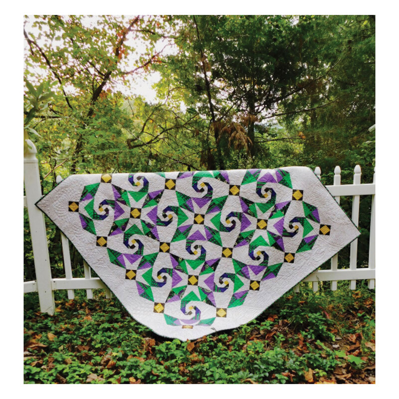 Image of completed quilt draped over a white picket fence 
