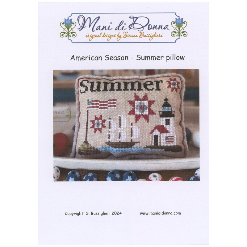 Front of pattern showing the completed cross stitch on a pillow staged in a bowl with patriotic beads