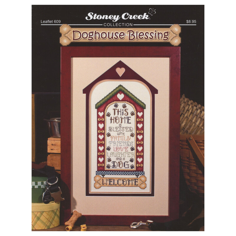 Front of cross stitch pattern showing the finished design framed and displayed on a table with dog treats and a collar and leash