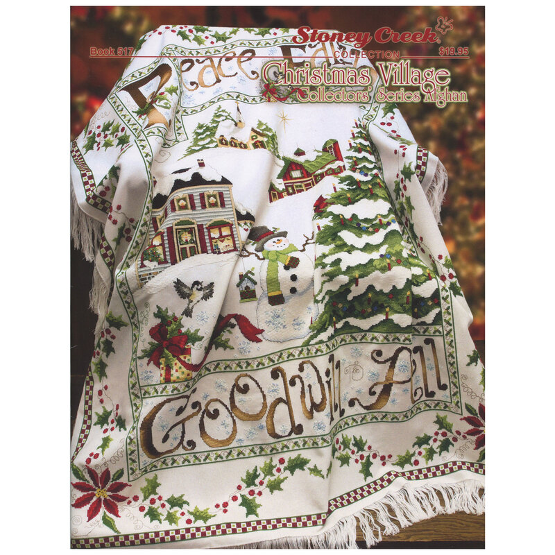 Front of cross stitch pattern showing the finished design on a blanket draped over a chair with christmas decorations in the background
