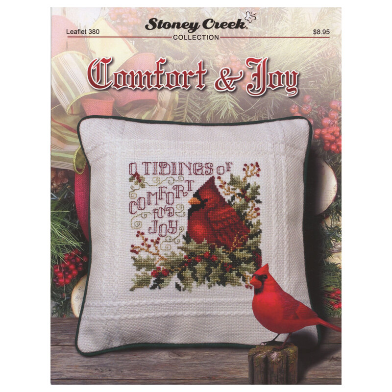 Front of cross stitch pattern showing the finished design on a pillow with a cardinal in the foreground displayed in front of a Christmas wreath