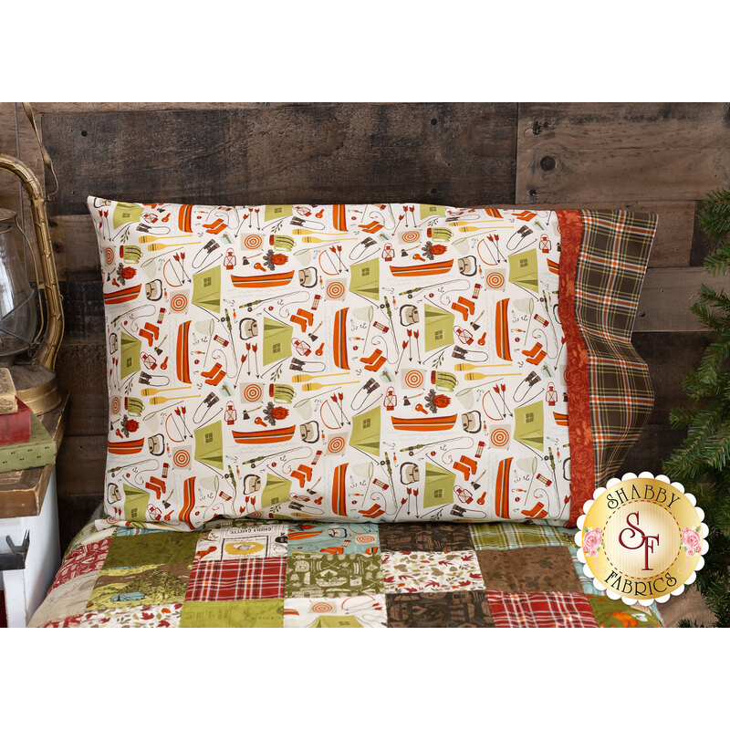 A shot of the Magic Pillowcase in Cream, staged on a bed with a matching patchwork quilt in a cabin setting.
