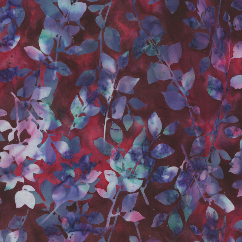 Dark red batik fabric with mottled blue, purple, and aqua leaves and sprigs throughout.