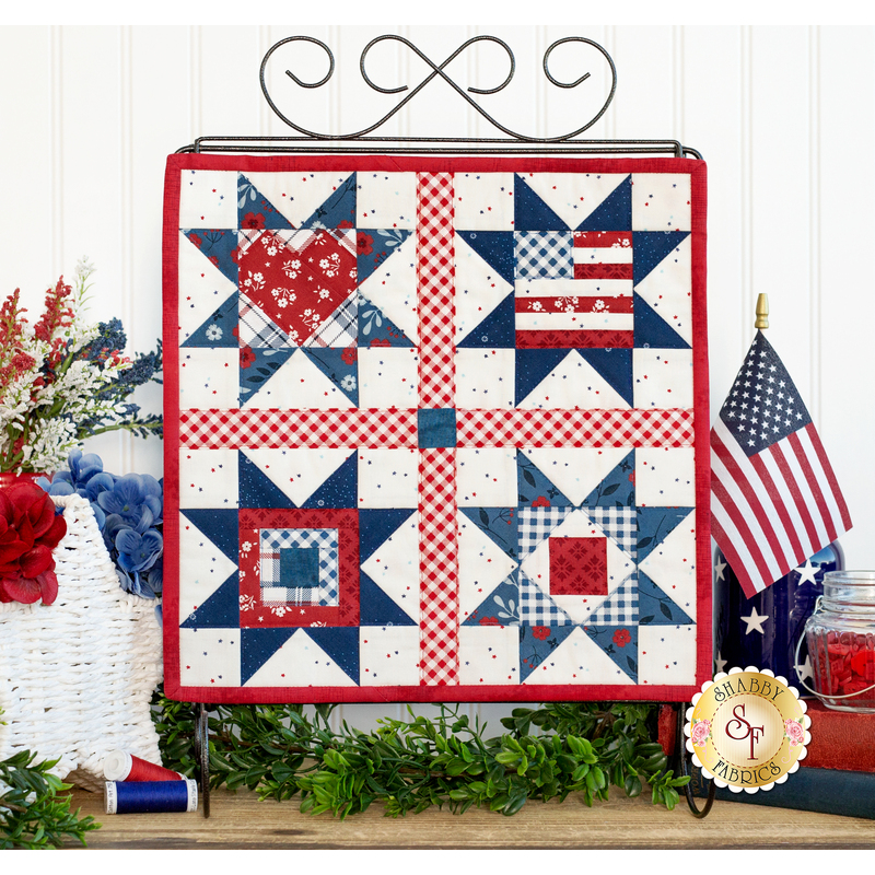 The completed Foundation Paper Piecing Series 2 July wall hanging, staged on a rustic wood countertop with coordinating patriotic decor.