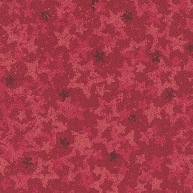 Swatch of warm red fabric with tossed and layered tonal red stars.