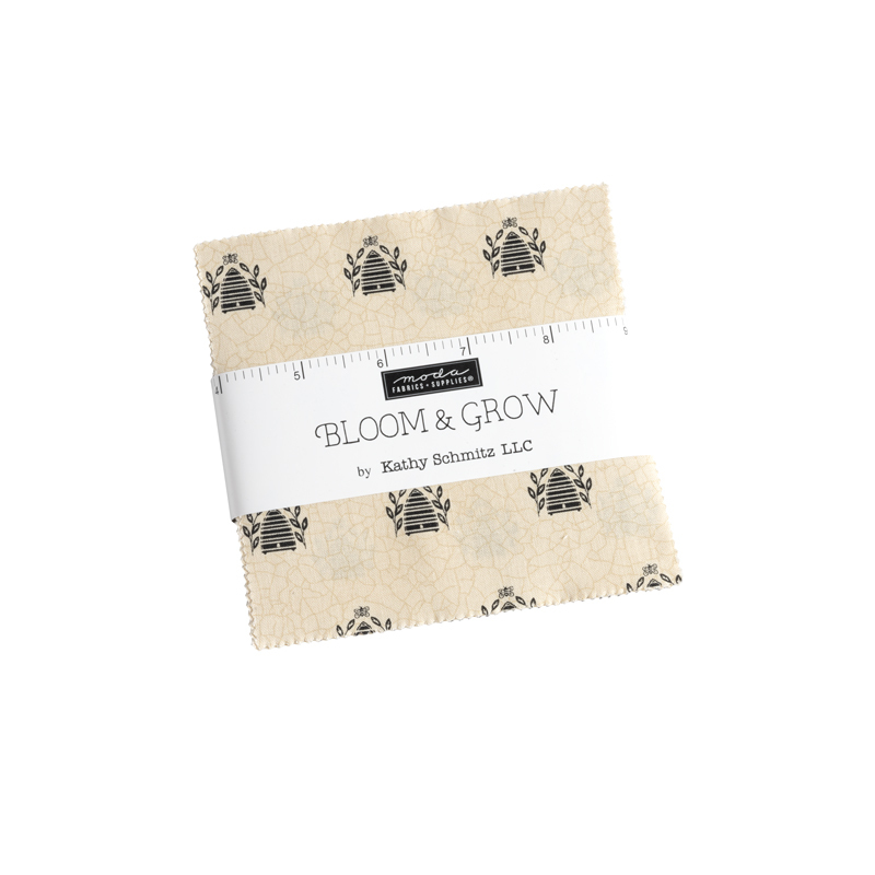 A square bundle of tan fabrics wrapped in a white Moda Fabrics ruler ribbon against a white background