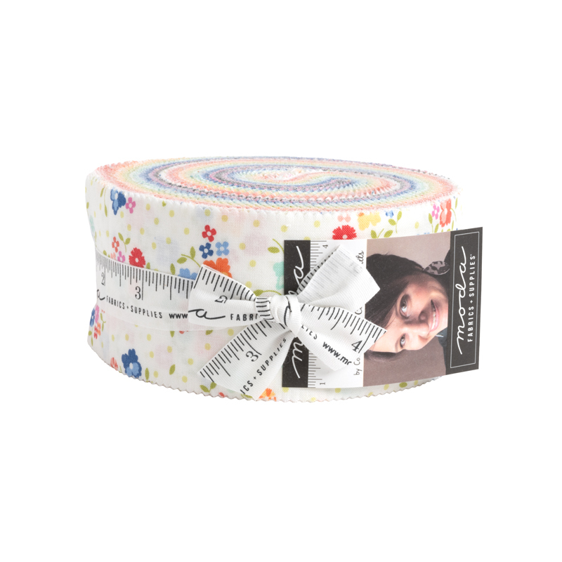 A circular roll of white and multi-colored fabrics wrapped in a white ruler print bowtie