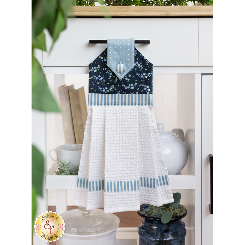 The completed Shoreline Hanging Towel in dark blue, hung from a kitchen cart drawer handle and staged with coordinating decor.
